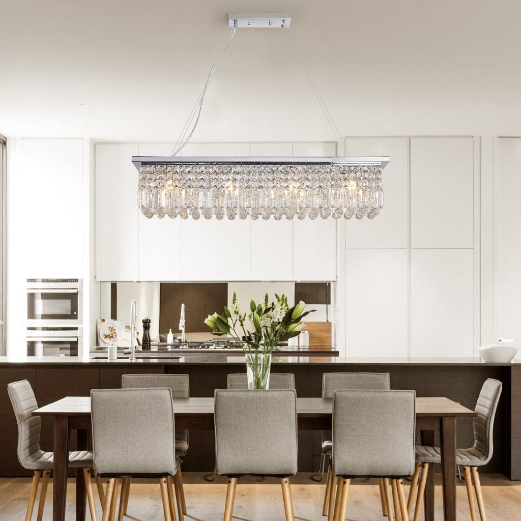 Modern dining room with a crystal chandelier, table, and chairs.