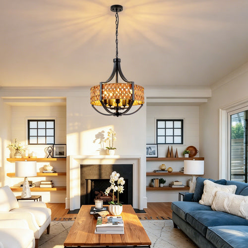 A modern chandelier with a black metal frame and a woven natural wood shade hangs in a bright, contemporary living room with a blue sofa, wooden coffee table, and fireplace.