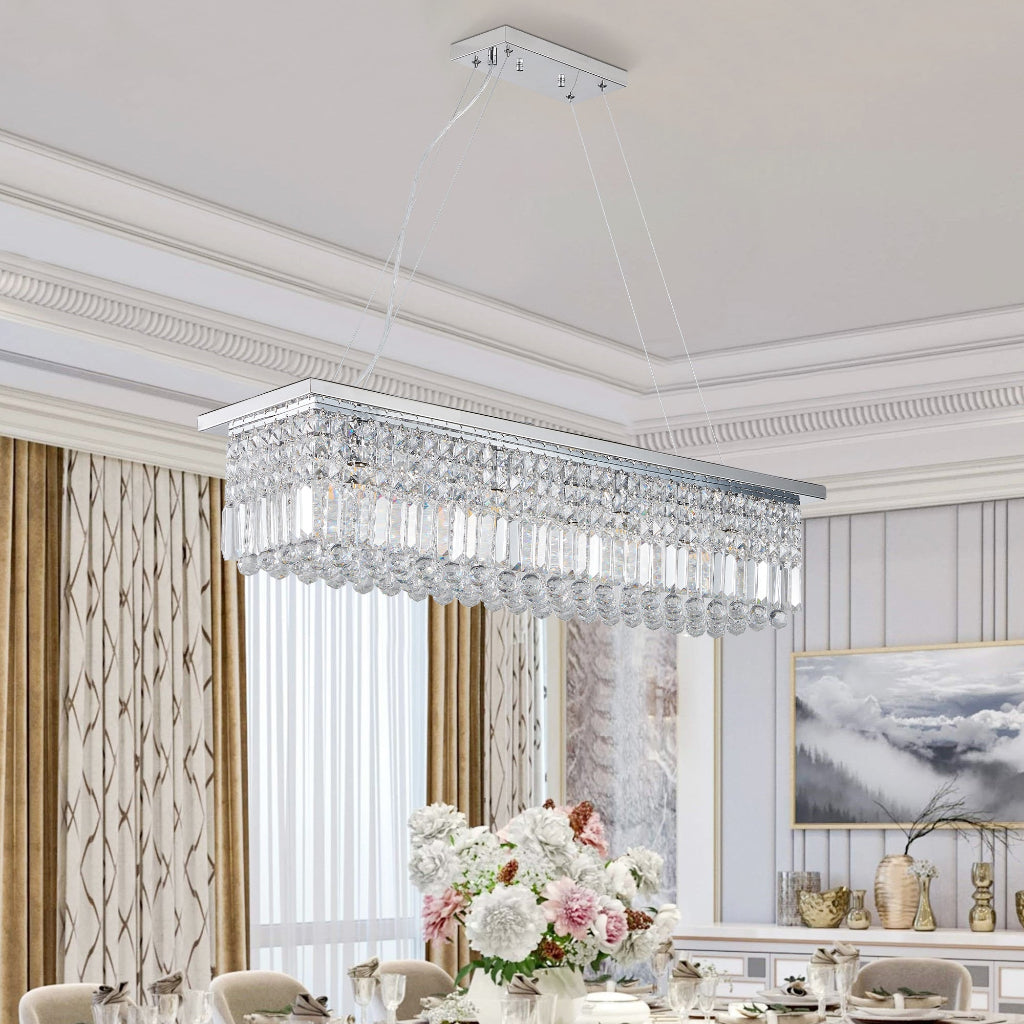 Crystal chandelier hanging in a dining room with floral centerpiece and artwork on the wall.