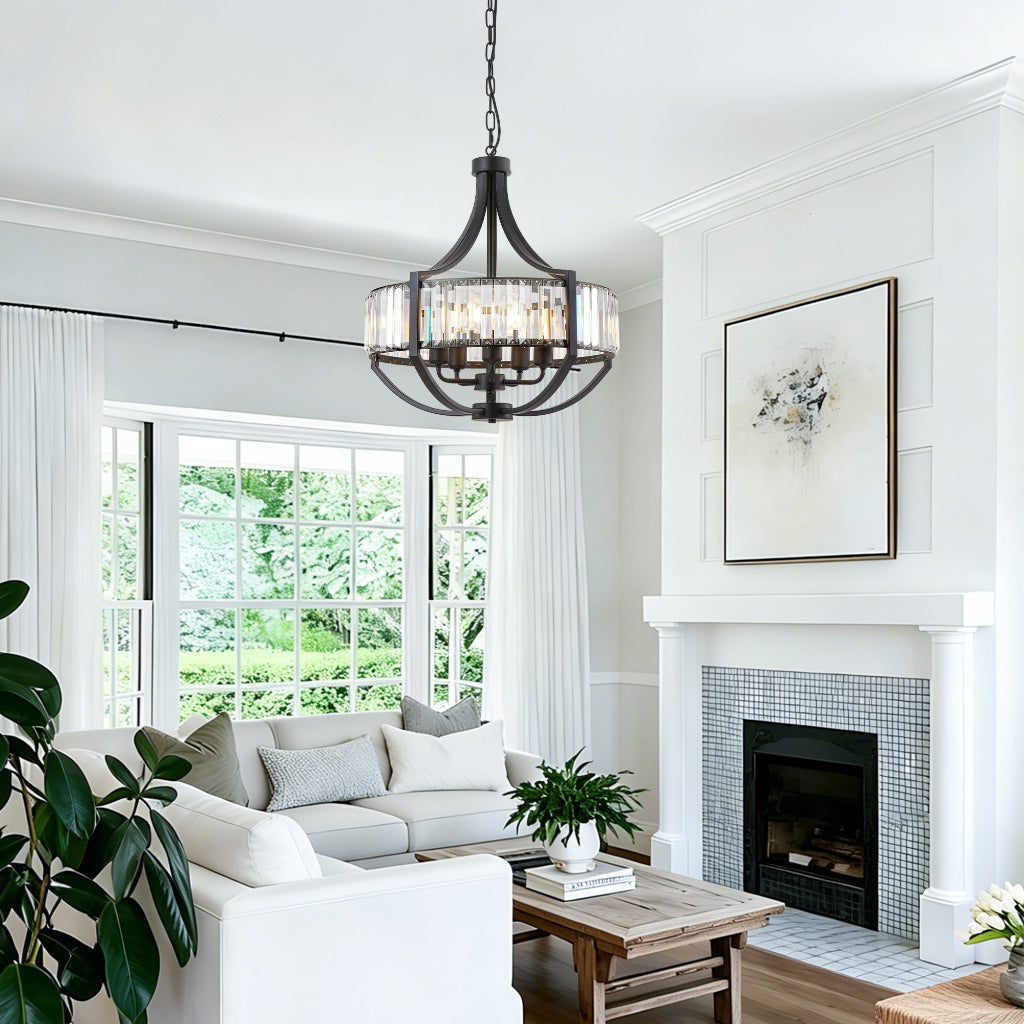 A multi-light chandelier with a dark metal frame and clear glass shades hangs in a bright, modern living room with a white fireplace, gray tile, and a light gray sectional sofa.